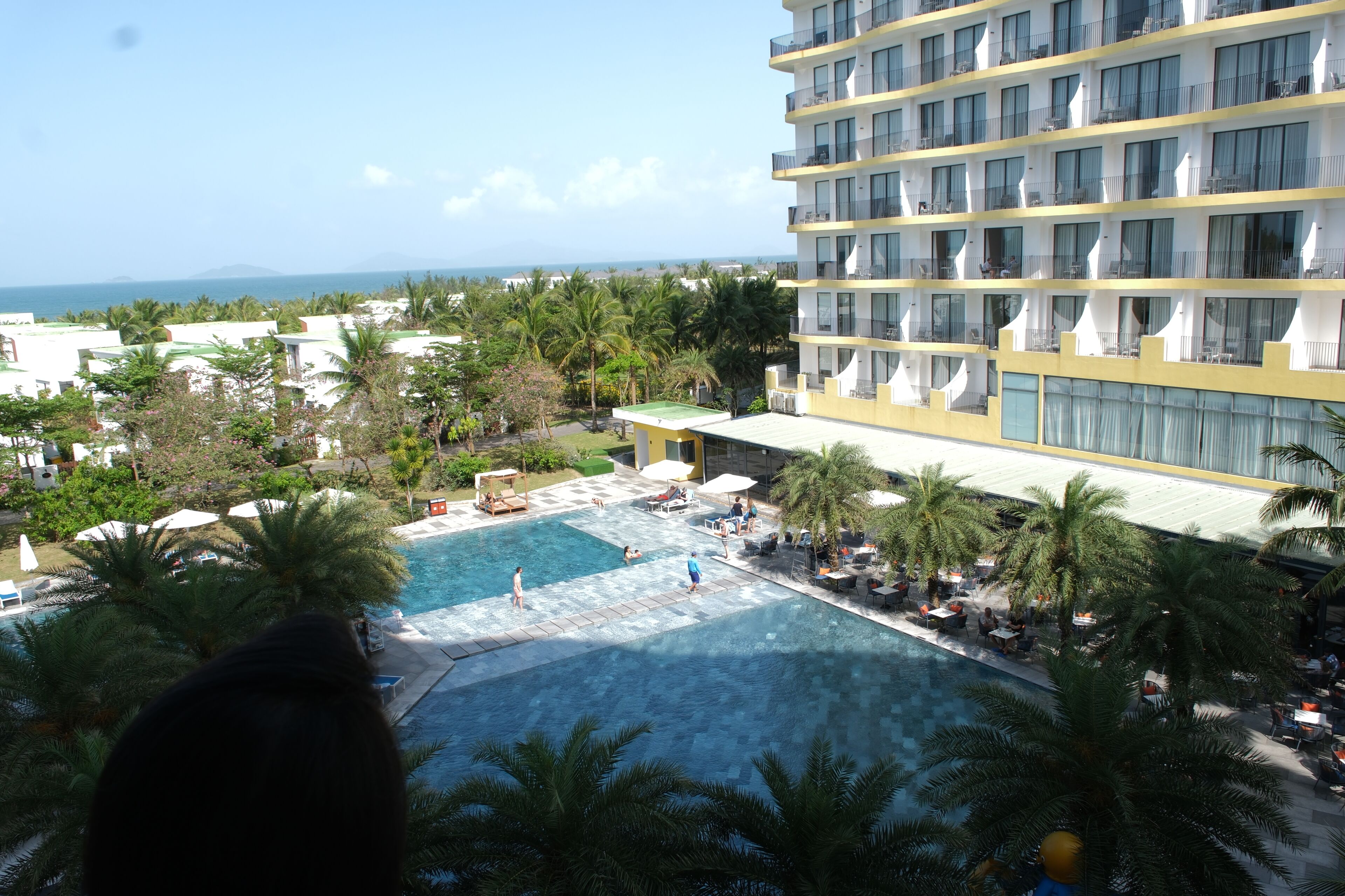 A hotel with a pool area, palm trees, and a view of the ocean.