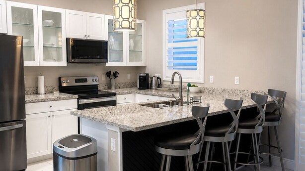 Una cocina moderna con encimera de granito, electrodomésticos de acero inoxidable y una zona de bar con taburetes.