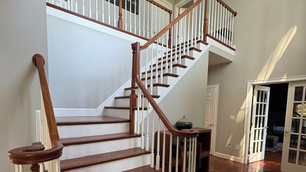 Un escalier en bois avec des rampes blanches menant à l’étage supérieur.