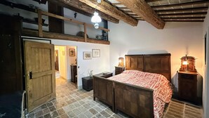 Un dormitorio rústico con cama de madera, cómoda, mesita y lámpara colgante.