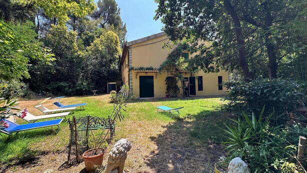 Un patio con piscina, mobiliario exterior y un edificio con puerta y ventanas.