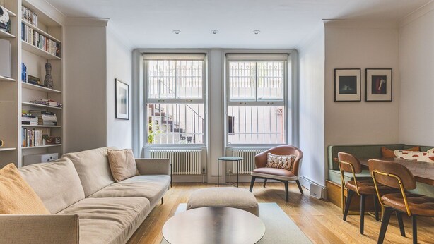 A living room with a sofa, a coffee table, a chair, a dining table with chairs, and a bookshelf. - Notting Hill Patio Retreat (London)