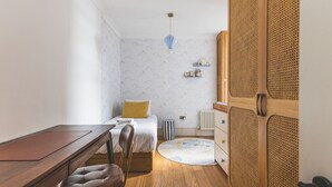 A bedroom with a bed, bedside table, chair, wooden floor, and a wardrobe with a woven design. - Notting Hill Patio Retreat (London)