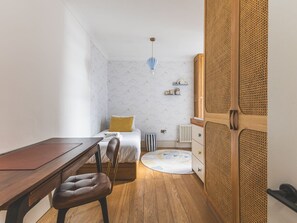 A bedroom with a bed, bedside table, chair, wooden floor, and a wardrobe with a woven design. - Notting Hill Patio Retreat (London)