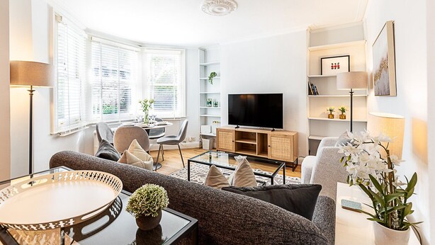 Una sala de estar moderna con un sofá, una mesa de centro, un televisor y un comedor con mesa y sillas.