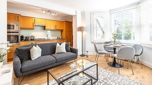 Una sala de estar moderna con un sofá gris, una mesa de centro de vidrio y un comedor con una mesa y sillas.