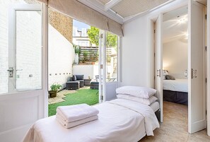 Ein Schlafzimmer mit einem Bett, einer kleinen Sitzecke mit Tisch und Stühlen sowie Blick ins Freie.