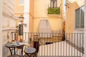 A narrow alleyway with a small table set for two, a hanging laundry, and a balcony with a metal railing. - Vecchia Bari Castello Svevo | Historic Charm with Balcony  (Bari)