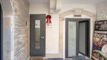 A hotel entrance with a door, a welcome mat, and a signboard.