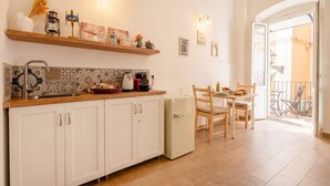 A kitchen with white cabinets, a countertop, and a refrigerator. There is a dining area with a table and chairs.