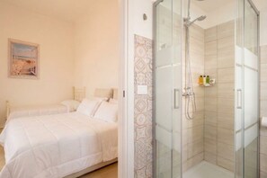 A hotel room with two beds, a shower, and a patterned wall. - Vecchia Bari Castello Svevo | Historic Charm with Balcony  (Bari)
