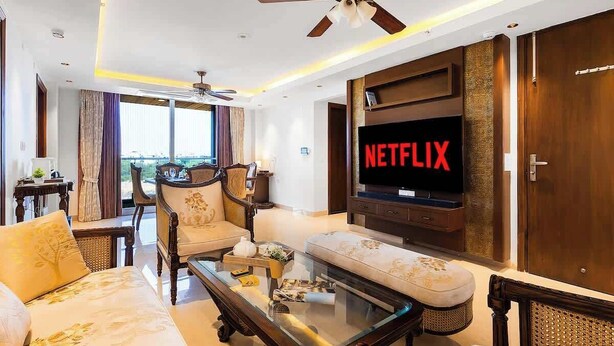 Ein modernes Wohnzimmer mit Fernseher, Deckenventilator und Blick auf die Stadt.