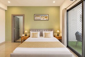 A hotel room with a bed, two bedside tables, a nightstand, a framed picture on the wall, and a sliding glass door leading to a balcony.