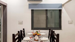 A dining area with a table set for four, a window with a view, and an air conditioning unit above the table.