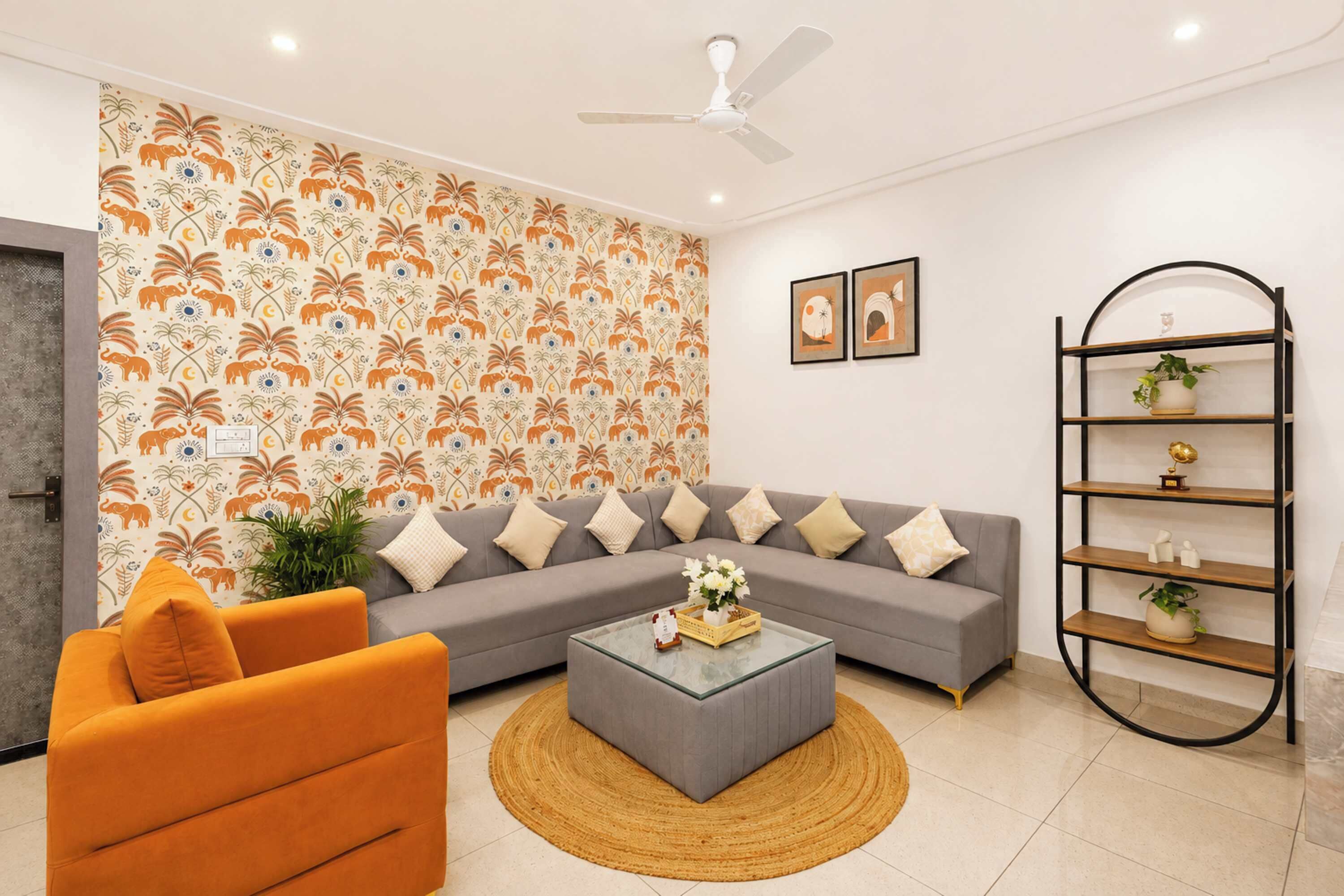 A modern living room with a grey sofa, orange armchair, and a coffee table with a vase of flowers.
