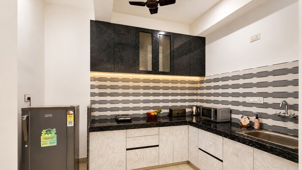 A modern kitchen with a black countertop, white cabinets, and a striped backsplash.