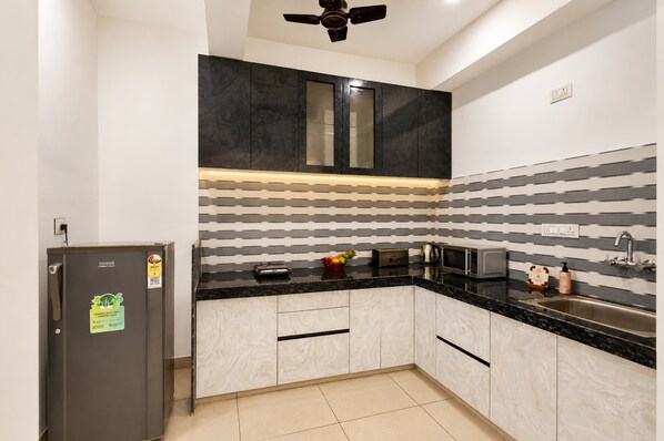 A modern kitchen with a black countertop, white cabinets, and a striped backsplash.