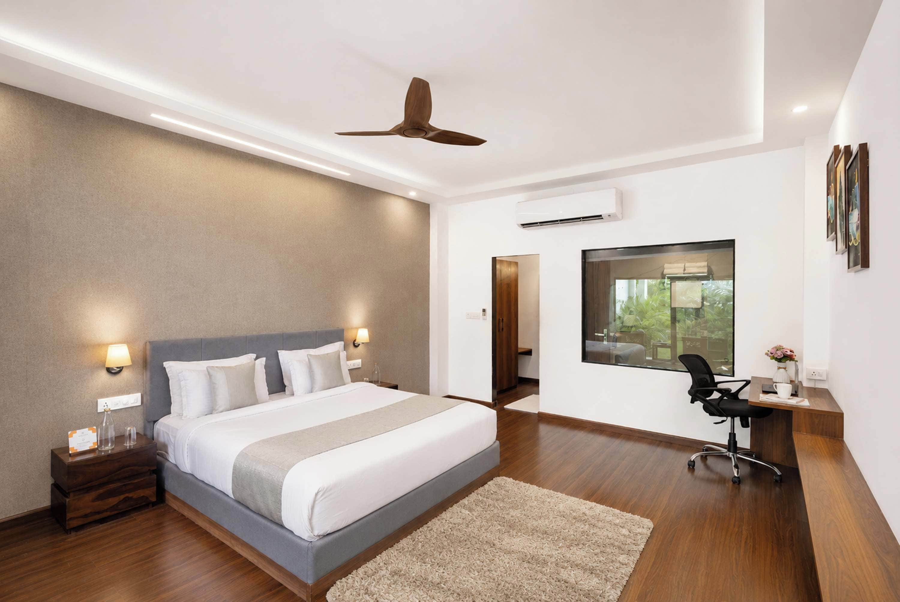 Une chambre d’hôtel moderne avec un grand lit, un bureau et une vue sur la verdure.