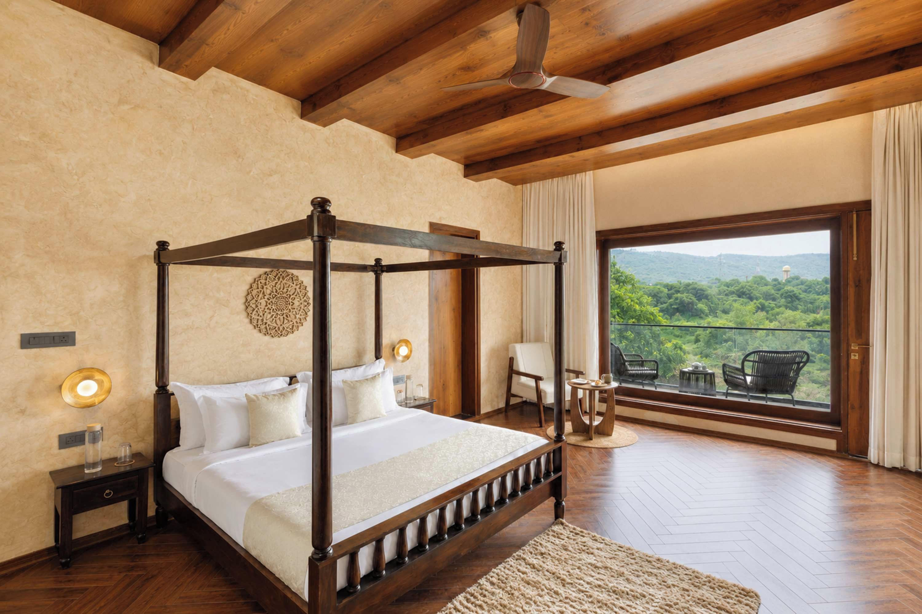 Una cama con dosel frente a un amplio ventanal con vistas a un paisaje exuberante.