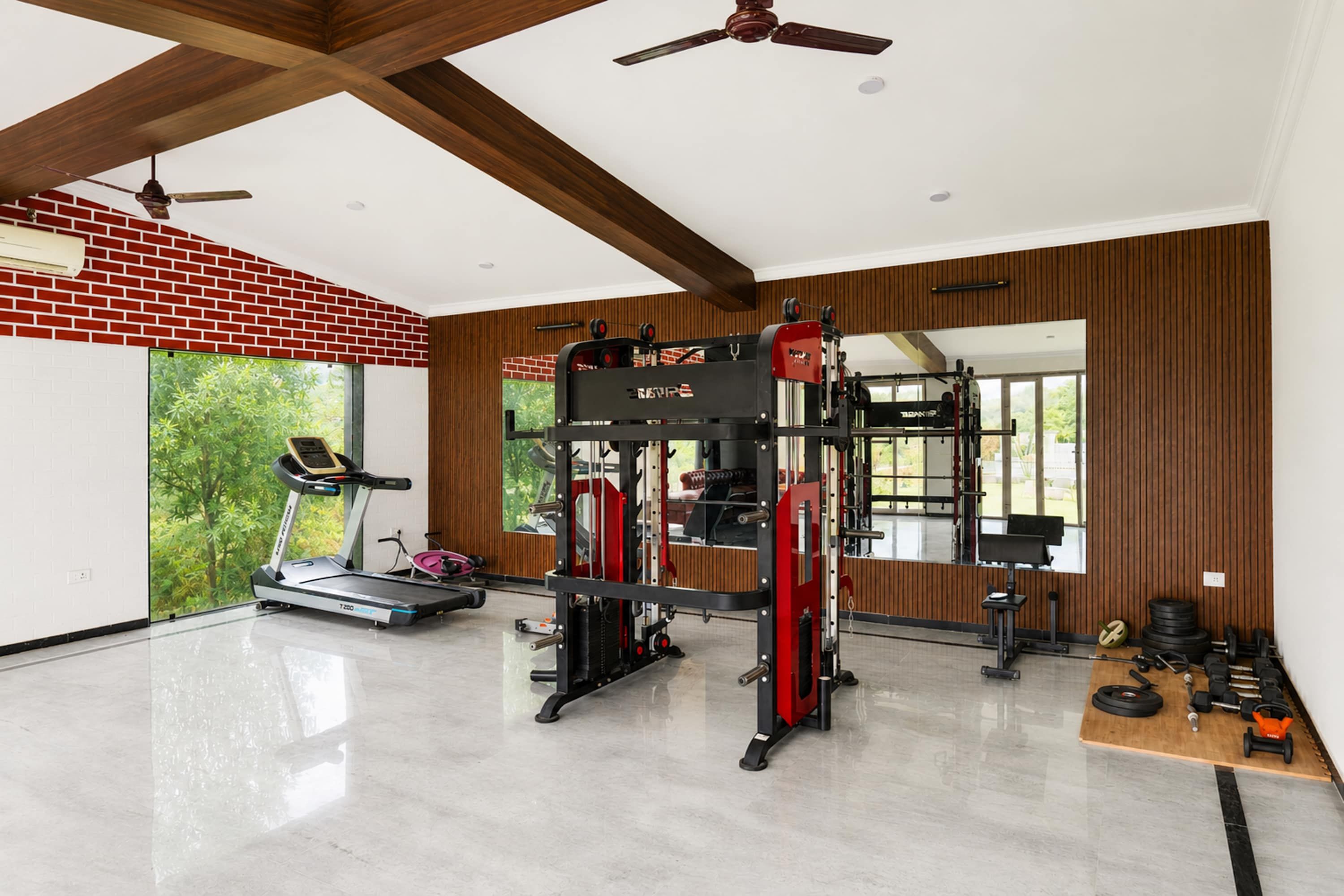 A gym with a treadmill, weightlifting equipment, and a mirror.