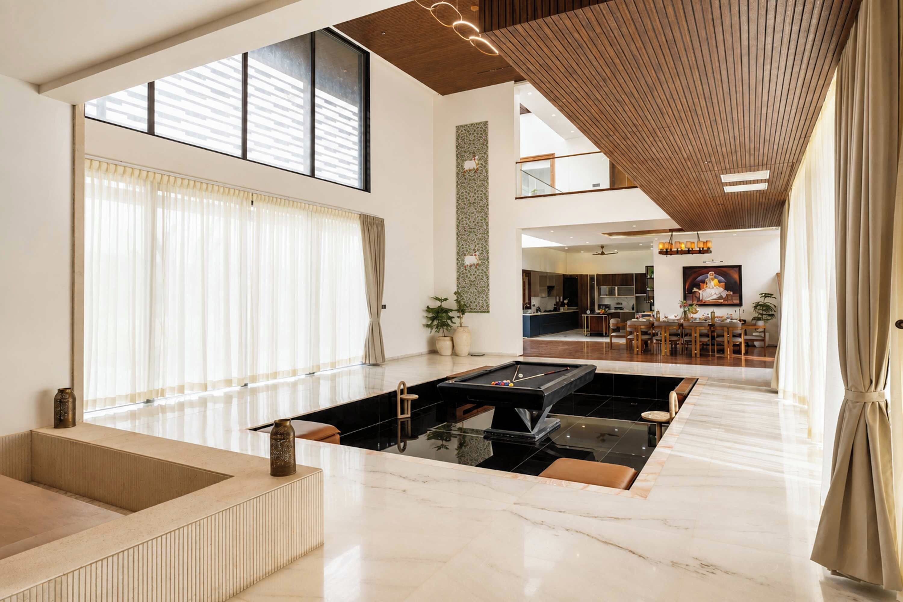 Amplia sala de estar con mesa de billar, ventanas grandes y un techo alto con vigas de madera.