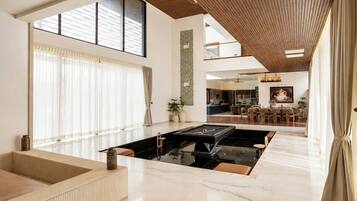 Amplia sala de estar con mesa de billar, ventanas grandes y un techo alto con vigas de madera.