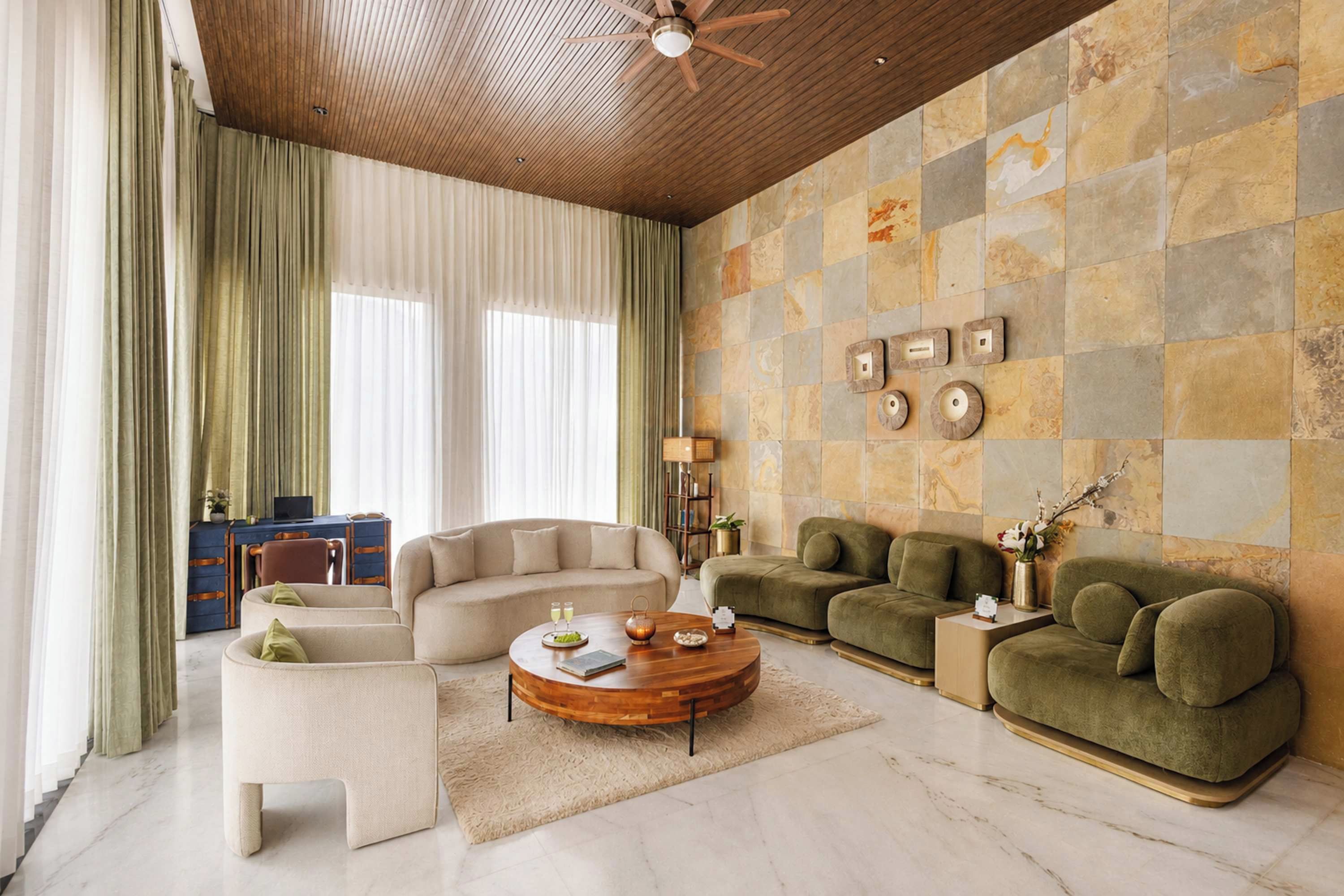 Ein modernes Wohnzimmer mit Holzboden, einer Steinwand und einer Kombination aus Sofas und Sesseln.