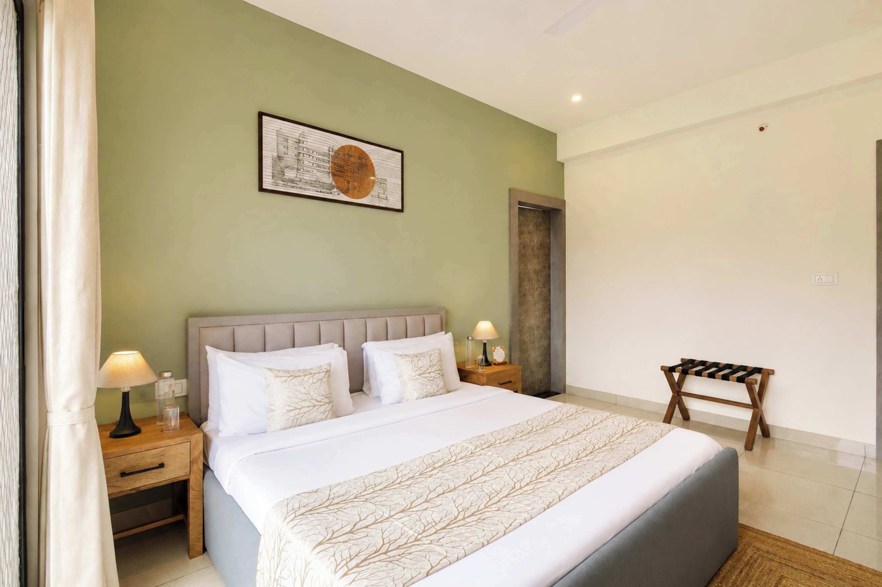 A hotel room with a bed, nightstands, a lamp, a picture on the wall, and a bench.