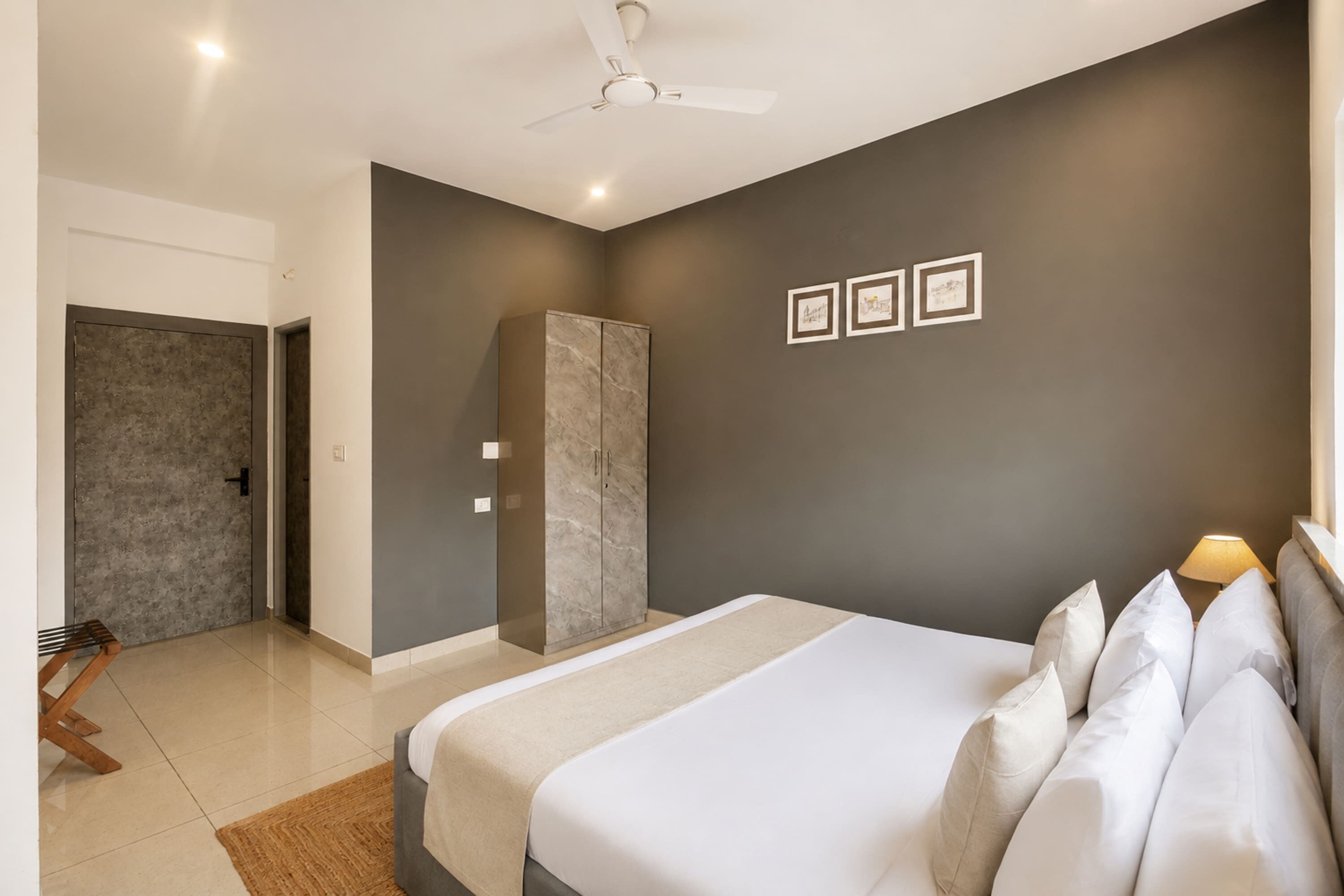 Un dormitorio moderno con cama, armario, ventilador de techo y cuadros en la pared.