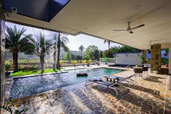 A pool area with a view of palm trees and a mountain in the background.