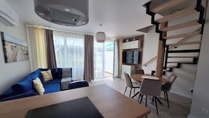 Ein modernes Wohnzimmer mit einer Couch, einem Esstisch und einer Treppe.