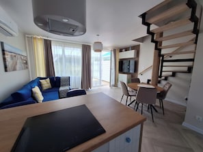 Ein modernes Wohnzimmer mit einer Couch, einem Esstisch und einer Treppe.
