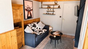 Ein gemütliches Zimmer mit einer Couch, einem kleinen Tisch, Holzböden und einem gerahmten Bild an der Wand.