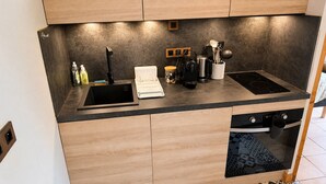Eine moderne Küche mit integriertem Geschirrspüler, einer schwarzen Induktionskochplatte und Holzschränken.