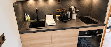 A modern kitchen with a built-in dishwasher, a black induction cooktop, and wooden cabinetry.