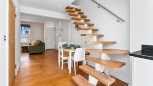 Ein modernes Interieur mit Treppe, Holzboden, Essbereich und Küche.