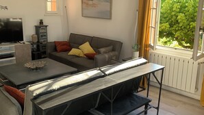 A living room with a sofa, a TV, a table, and a window with curtains. - A house in the heart of the vineyards and at the foot of Mont Ventoux (Mormoiron)