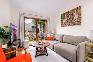 Ein Wohnzimmer mit einer Couch, einem Couchtisch, einem Fernseher und einem Bild an der Wand.