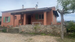 Una casa rústica amb paret de pedra, un porxo i vistes al camp.