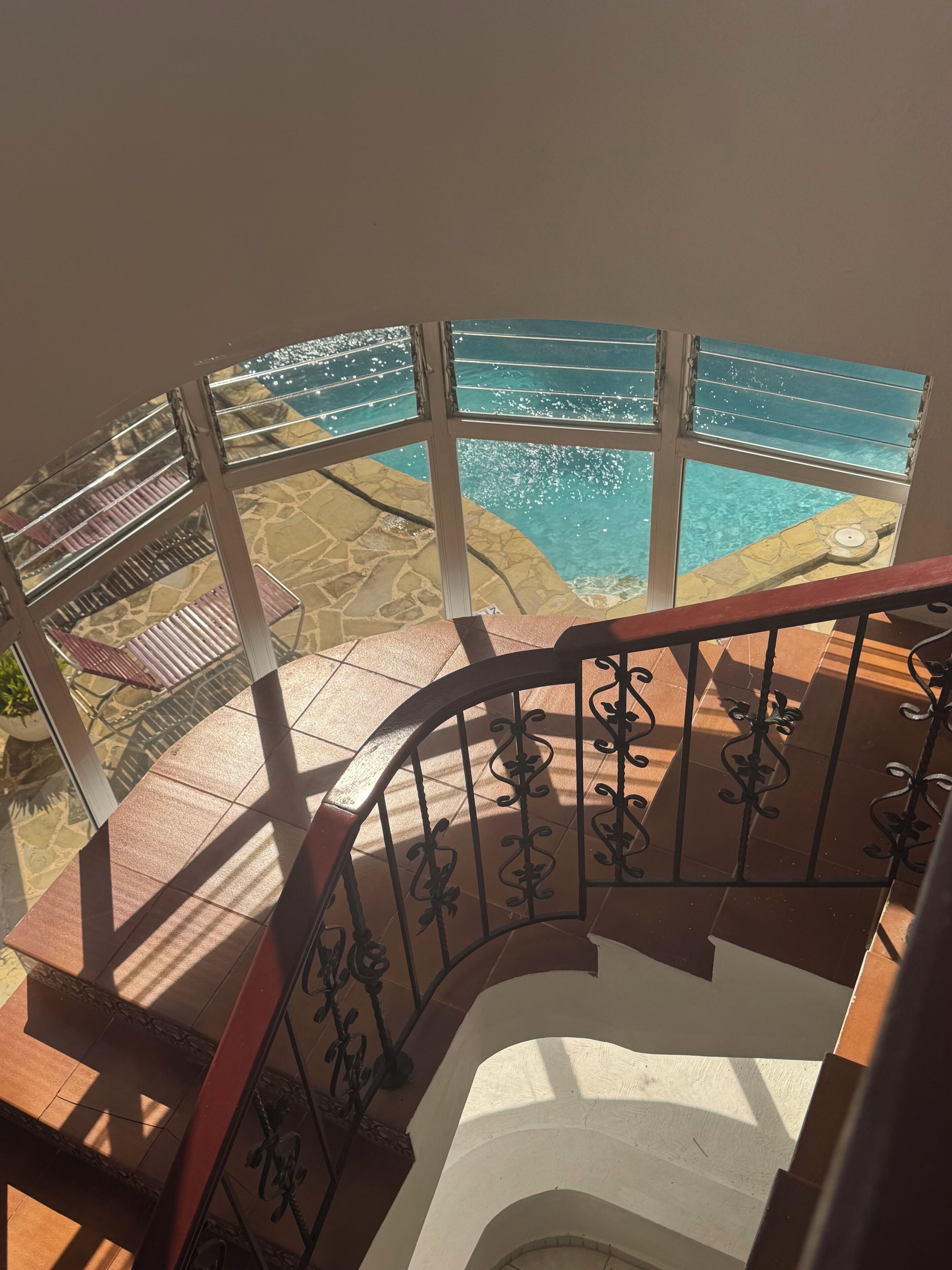 Eine Wendeltreppe mit Blick auf ein Schwimmbecken.