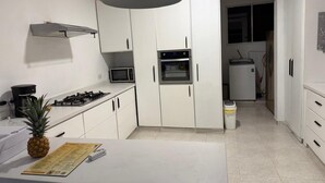 Eine Küche mit weißen Schränken, einer Mikrowelle, einem Herd und einem kleinen Kühlschrank.