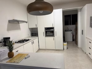 A kitchen with white cabinets, a microwave, a stove, and a small refrigerator. - Villa La Dueña, Cofresi Beach, Puerto Plata (Puerto Plata)