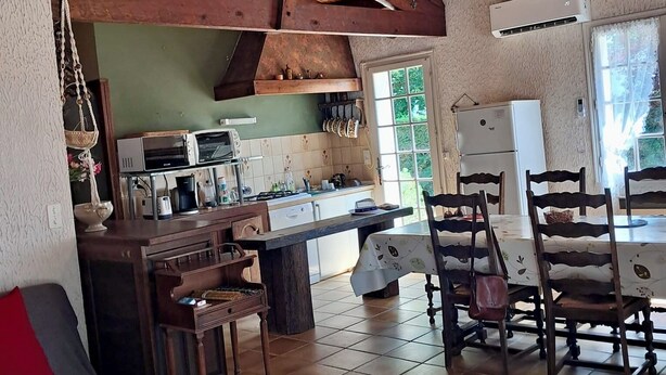 A rustic kitchen with wooden beams, a dining area with chairs, a sofa, and a table. - Dolus d'Oléron House - Sleeps 7 - Spacious and peaceful, ideal for a family vacation (Dolus-d'Oléron)