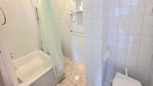 A bathroom with a bathtub, shower, toilet, and a towel rack.