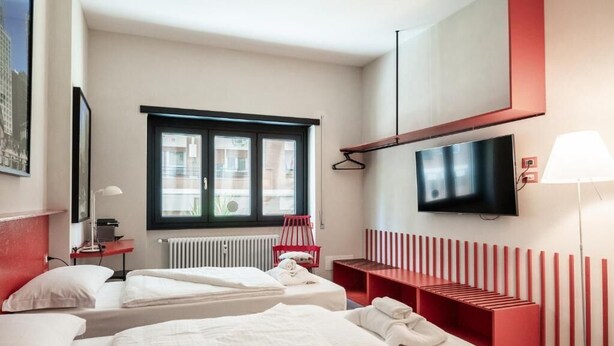 A hotel room with two beds, a TV, a window, a radiator, and a red bench. - Maison Ammiragli Vatican Rooms (Roma)