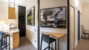 A modern kitchen with a built-in island, a dining area with a wooden table and chairs, and artwork on the walls. - Maison Ammiragli Vatican Rooms (Roma)