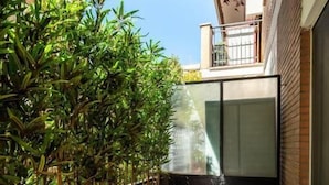 A small outdoor patio with a round table and wicker chairs, surrounded by potted plants. - Maison Ammiragli Vatican Rooms (Roma)