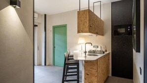 A compact kitchen with a central island, a microwave, and a green door in the background. - Maison Ammiragli Vatican Rooms (Roma)