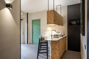 Cocina compacta con una isla central, microondas y una puerta verde al fondo.