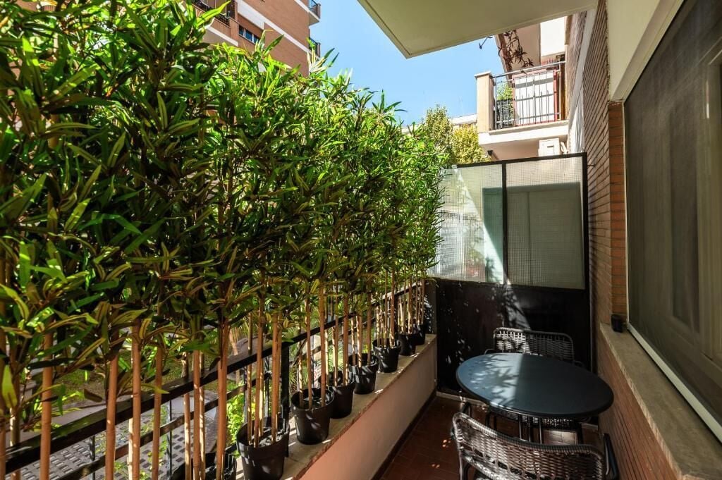 A balcony with potted plants, a table, and chairs.